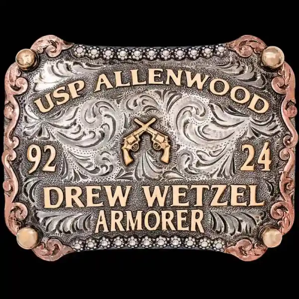 "Locked, loaded, and ready to turn heads. Our hand-crafted Hickory Belt Buckle is hand-engraved on a German Silver base, enhanced by a striking three-tone design. The buckle features a berry-edge detail along the top and bottom, complemented by intri